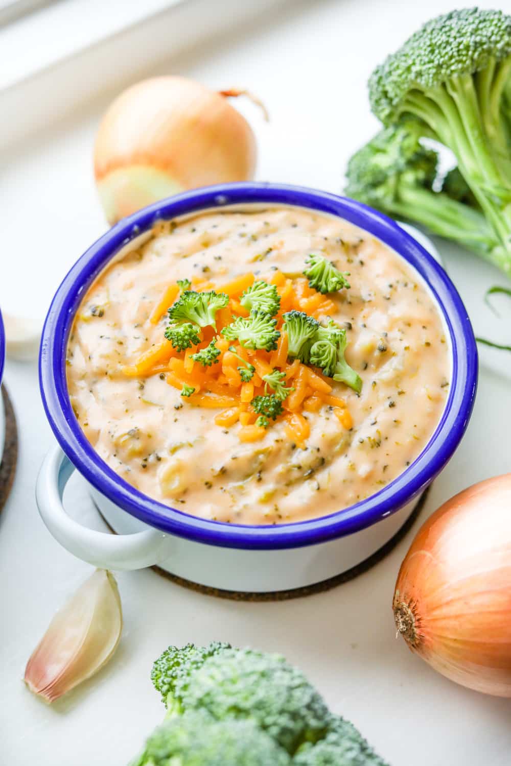 A bowl of keto broccoli cheese soup topped with cheddar cheese and bits of broccoli