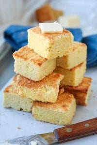 A large stack of cornbread in-front of a blue napkin.