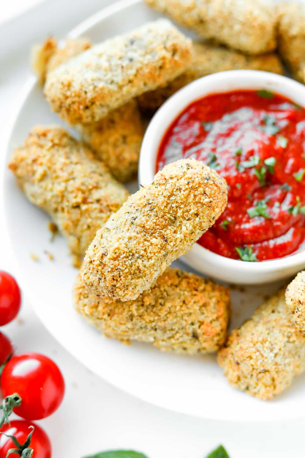 Keto mozzarella sticks on a plate with marinara sauce. 