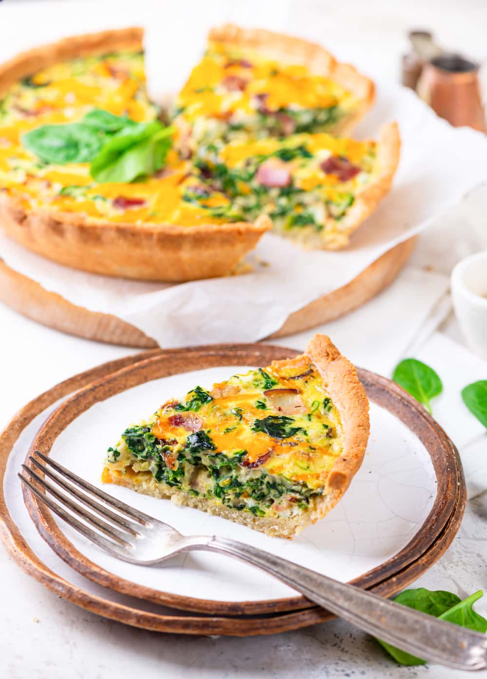 A slice of keto quiche set on a plate next to a fork.