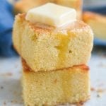 2 Slices of cornbread stacked on top of one another with melted butter on top of them.