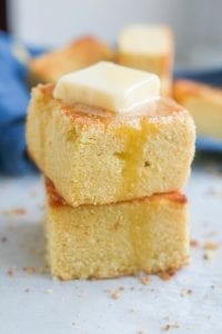 2 Slices of cornbread stacked on top of one another with melted butter on top of them.