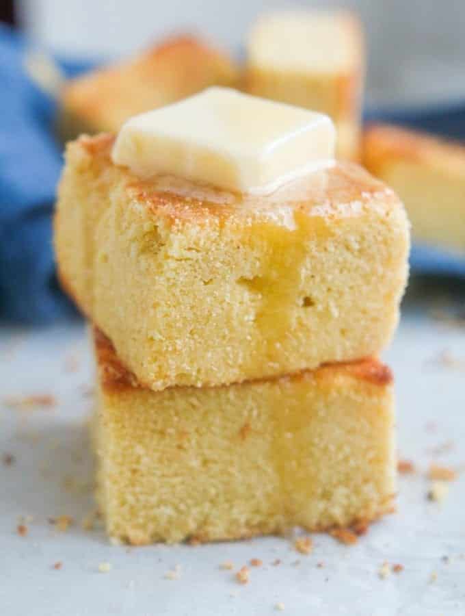 2 Slices of cornbread stacked on top of one another with melted butter on top of them.