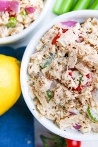 Two bowls of low carb tuna salad with a lemon, celery, and a blue napkin next to them.