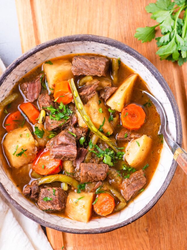 A bowl of beef stew with topped with fresh herbs.