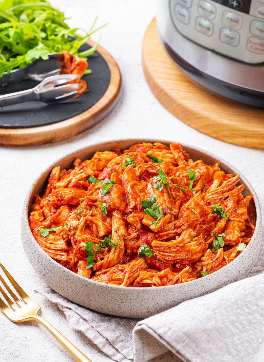 A bowl of bbq shredded chicken topped with fresh herbs.