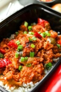 A container of BBQ chicken and veggies topped with green onions.