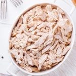 All white meat chicken shredded in a white casserole dish.