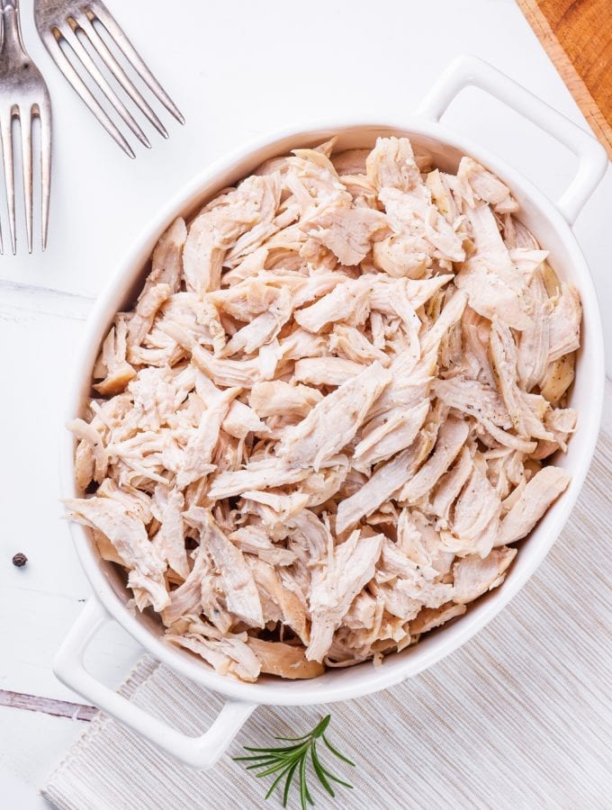 All white meat chicken shredded in a white casserole dish.