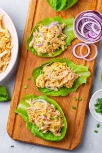 3 Shredded buffalo chicken lettuce wraps topped with green onions.