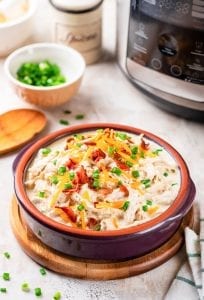 A bowl of keto crack chicken in front of an instant pot.