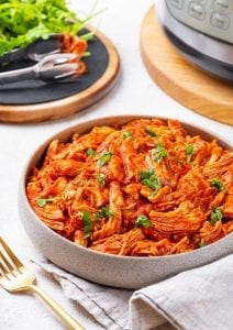 Shredded BBQ Chicken topped with fresh herbs in a grey bowl.