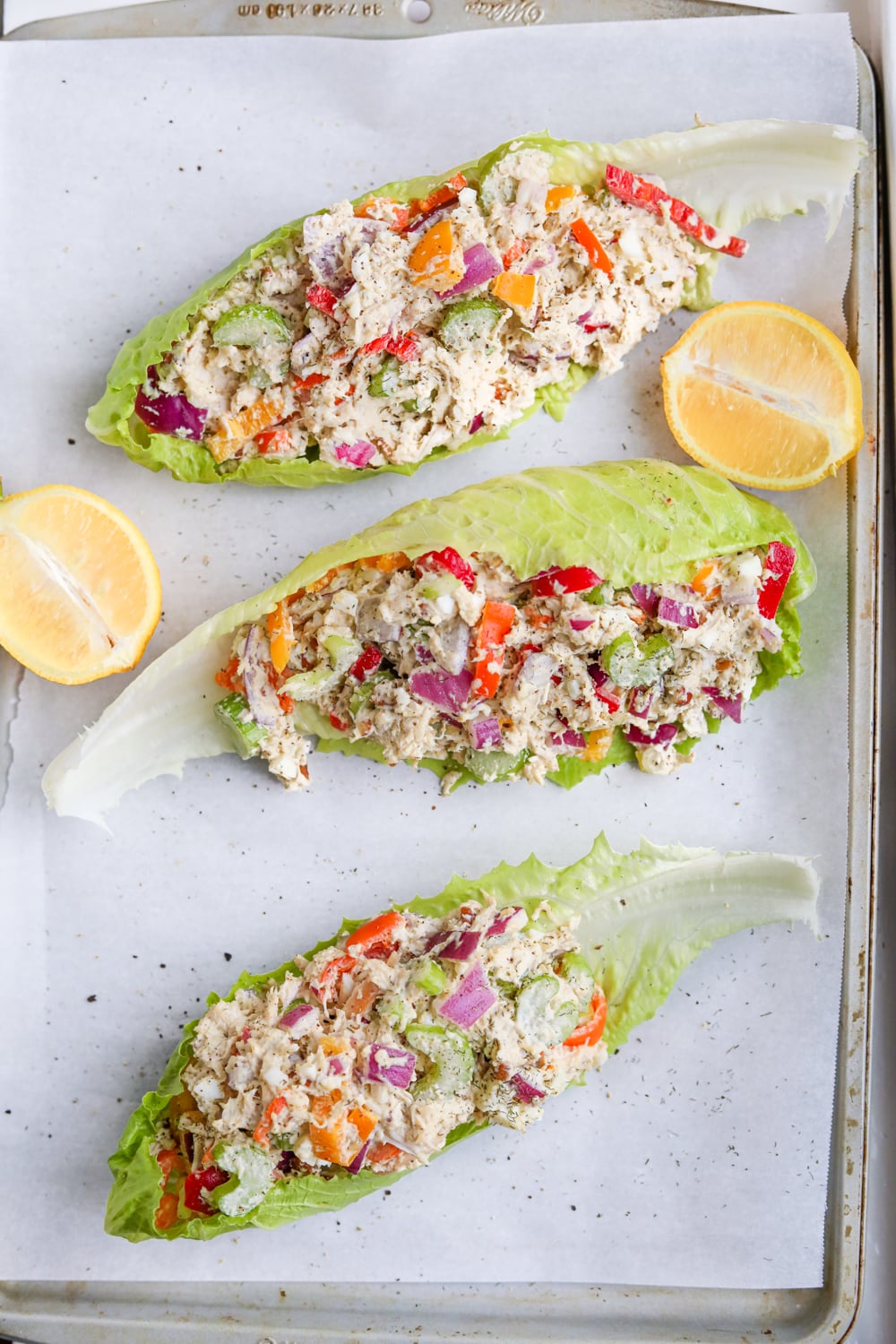 3 Chicken salad lettuce wraps on a tray with lemons.