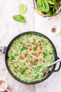 Creamed spinach in a cast iron pan topped with bacon.