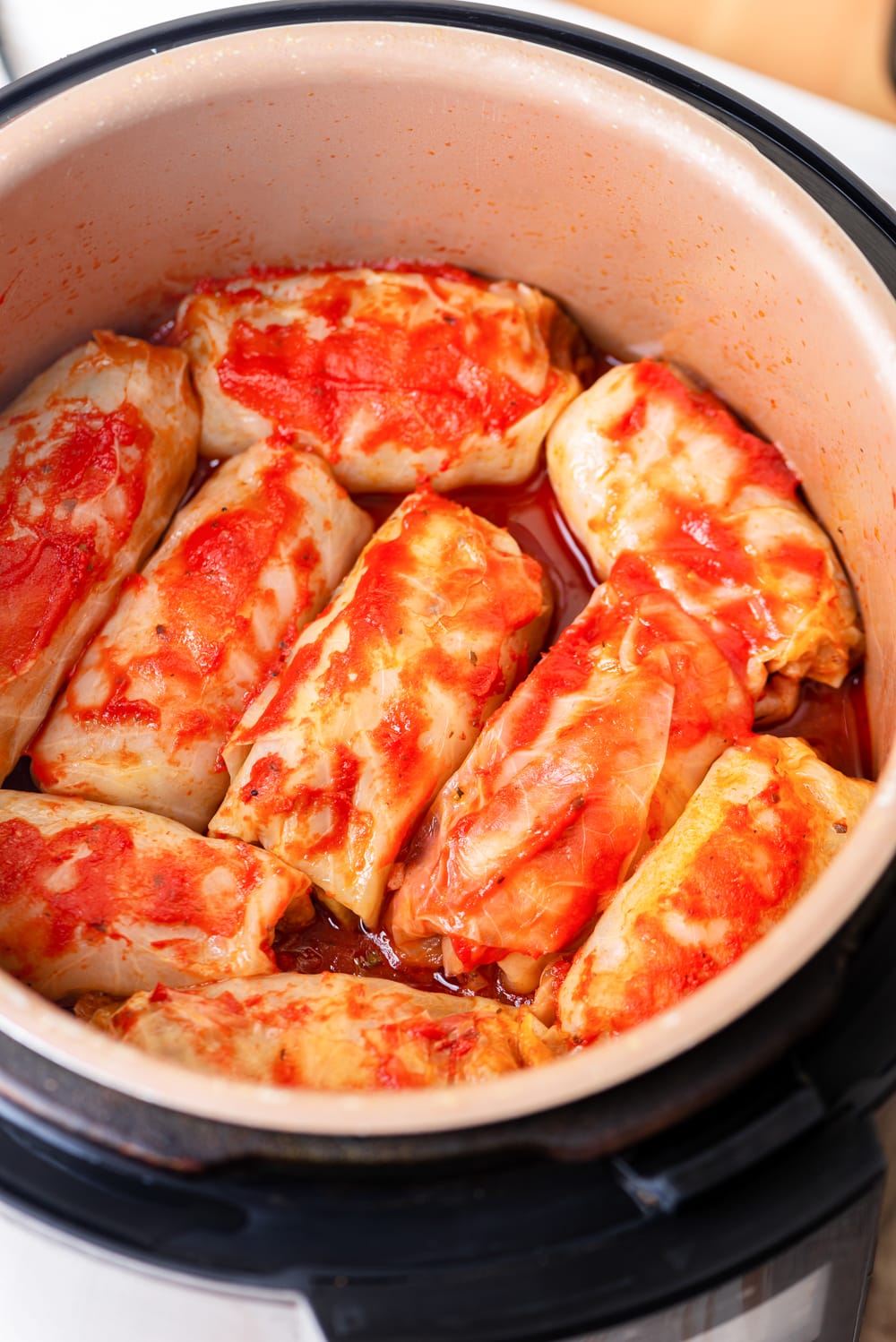 9 Keto cabbage rolls in an instant pot topped tomato sauce.