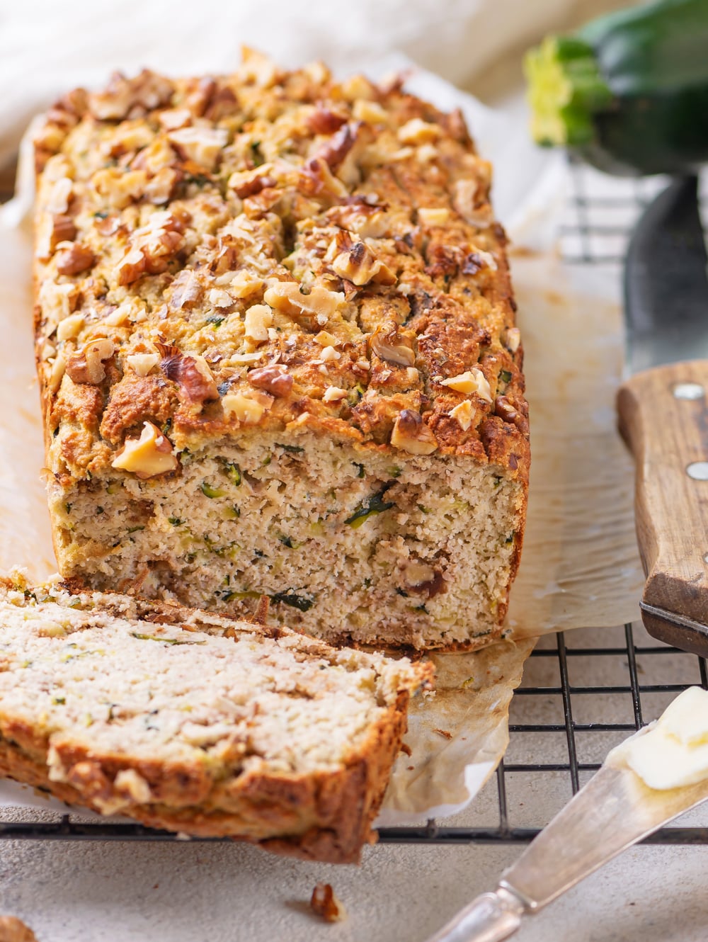 A loaf of low carb zucchini bread with a slice cut off of it.