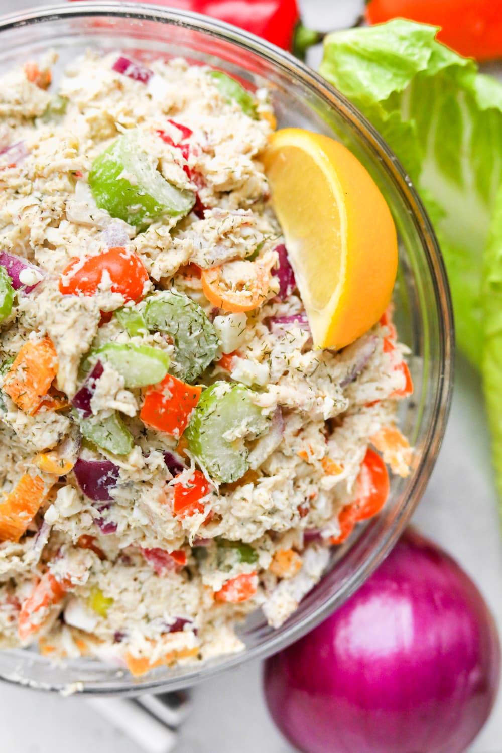 Keto chicken salad in a glass bowl with a slice of lemon in it.