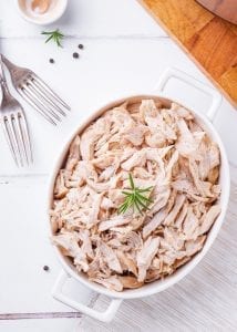 Shredded chicken in a casserole dish and garnished with salt and pepper.