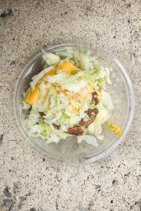 2 Burger patties topped with 2 slices of cheese, and topped with shredded lettuce, onions, and mustard.