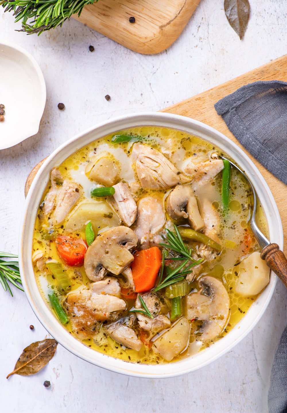 Chicken stew in a white bowl, with a spoon about to scoop some out.