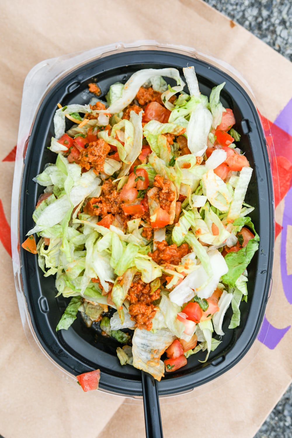 A bowl full of shredded lettuce, pico de gallo, and sauced ground beef.