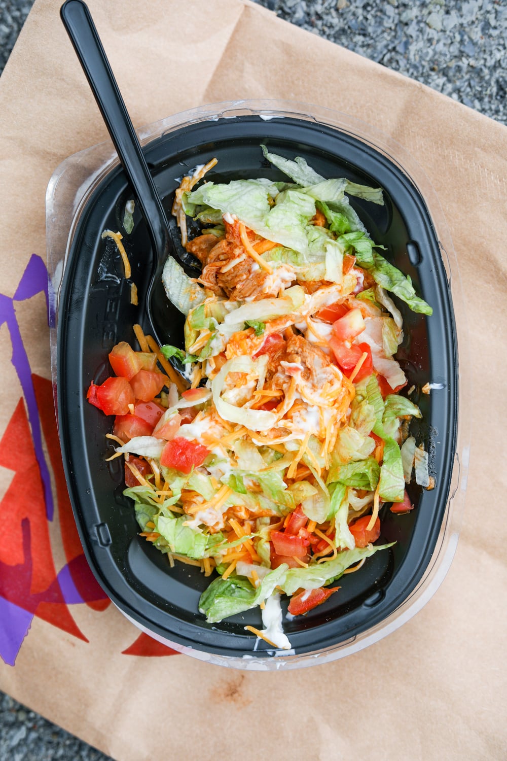 A bowl full of shredded lettuce, pico de gallo, shredded cheese, and sliced chicken.