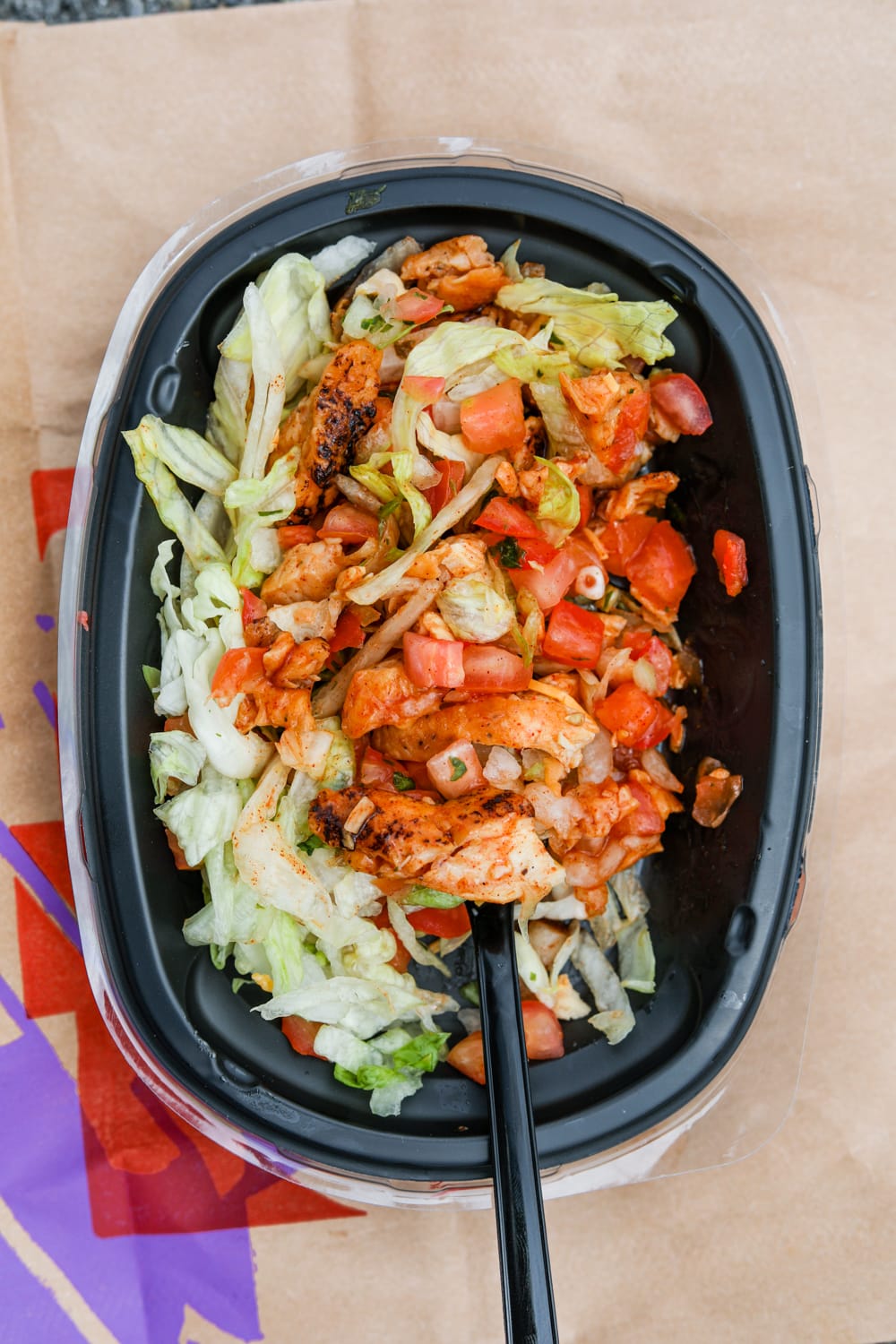 Shredded lettuce, pico de gallo, and char-grilled chicken in a small black bowl.