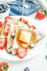 Syrup being drizzled on French toast and berries.