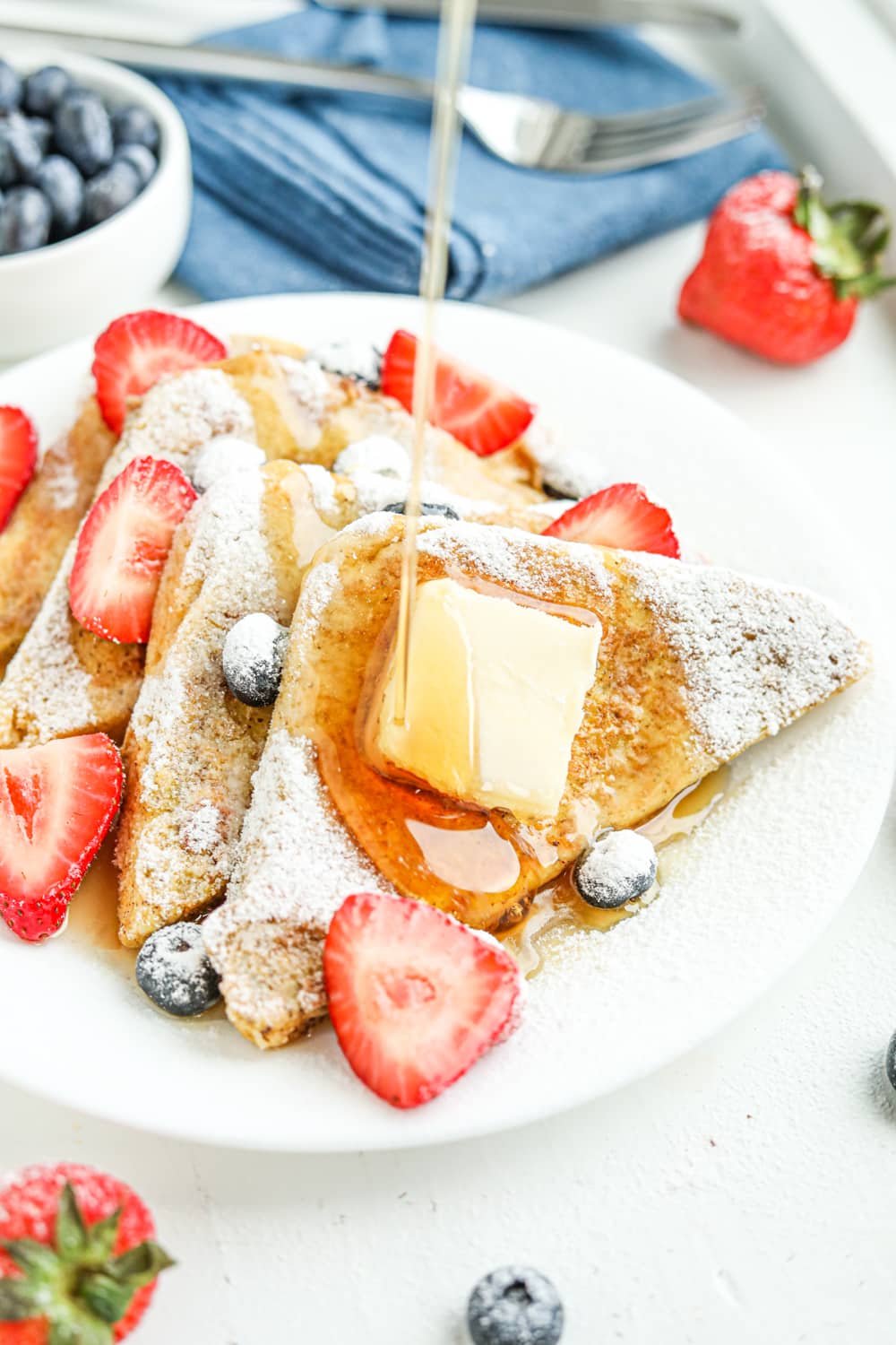 Syrup being drizzled on French toast and berries.