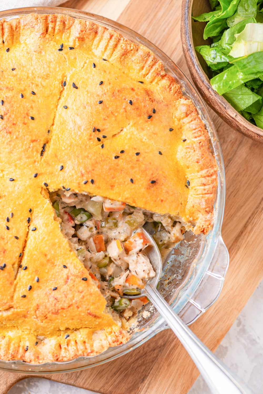 A spoon about to scoop out the filling from a chicken pot pie.