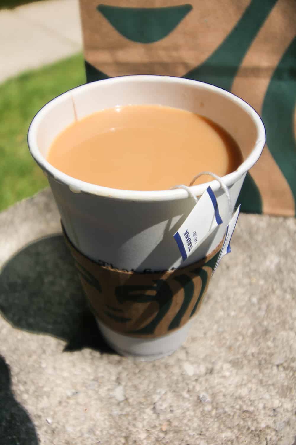 A large paper coffee cup filled with tea and cream.