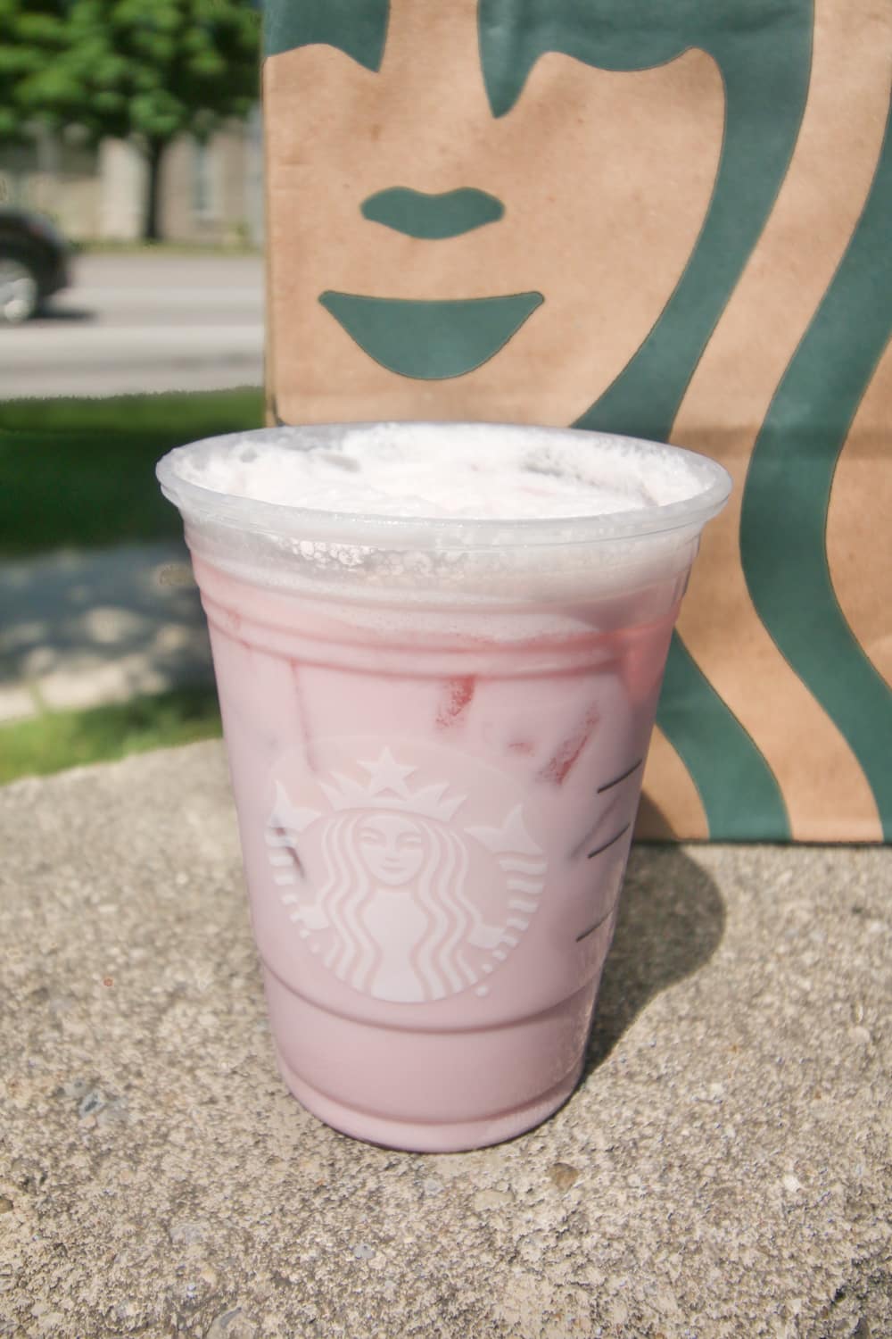 Pink tea mixed with cream and sweetener in a cup.