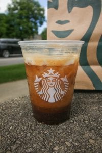 A plastic cup with 2 shots of espresso in it, poured over ice, and mixed with almond milk and keto sweetener.