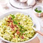 A bowl filled with egg salad that's topped with bacon and chives.