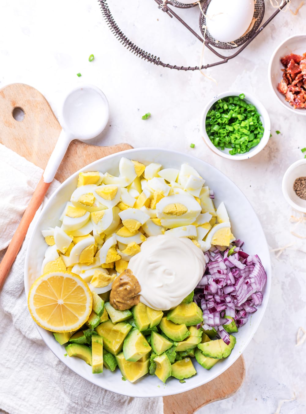 All of the ingredients to make an egg salad in a bowl, and about to be mixed.