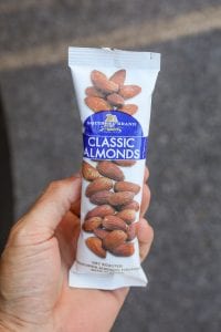 A hand holding a package of almonds.