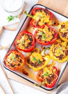 Bell peppers on baking sheet, cut in half, and filled with ground beef & cheddar cheese.