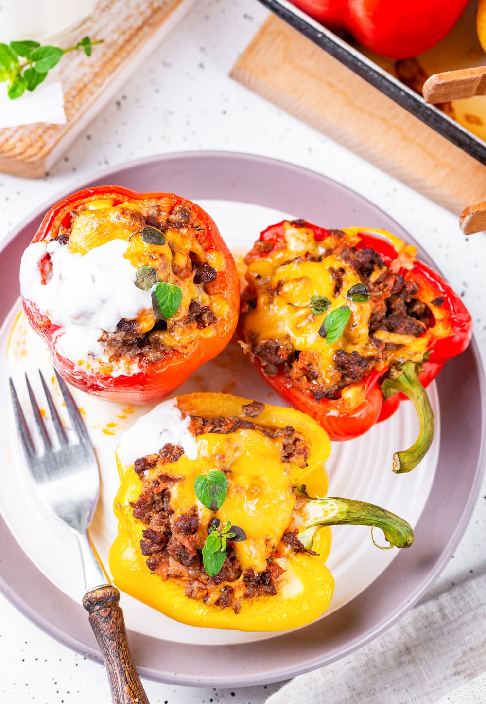 2 Red stuffed bell peppers and 1 yellow stuffed bell pepper on a plate.