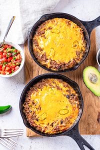 2 skillets filled with ground beef and topped with melted cheese.