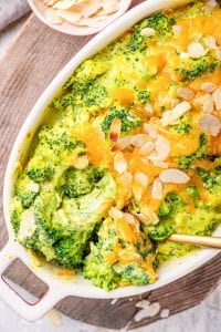 Cheese covered broccoli florets about to be served from a casserole dish.