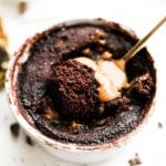 A fork about to take a piece of chocolate and peanut butter cake out of a mug.