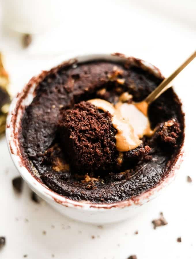 A fork about to take a piece of chocolate and peanut butter cake out of a mug.