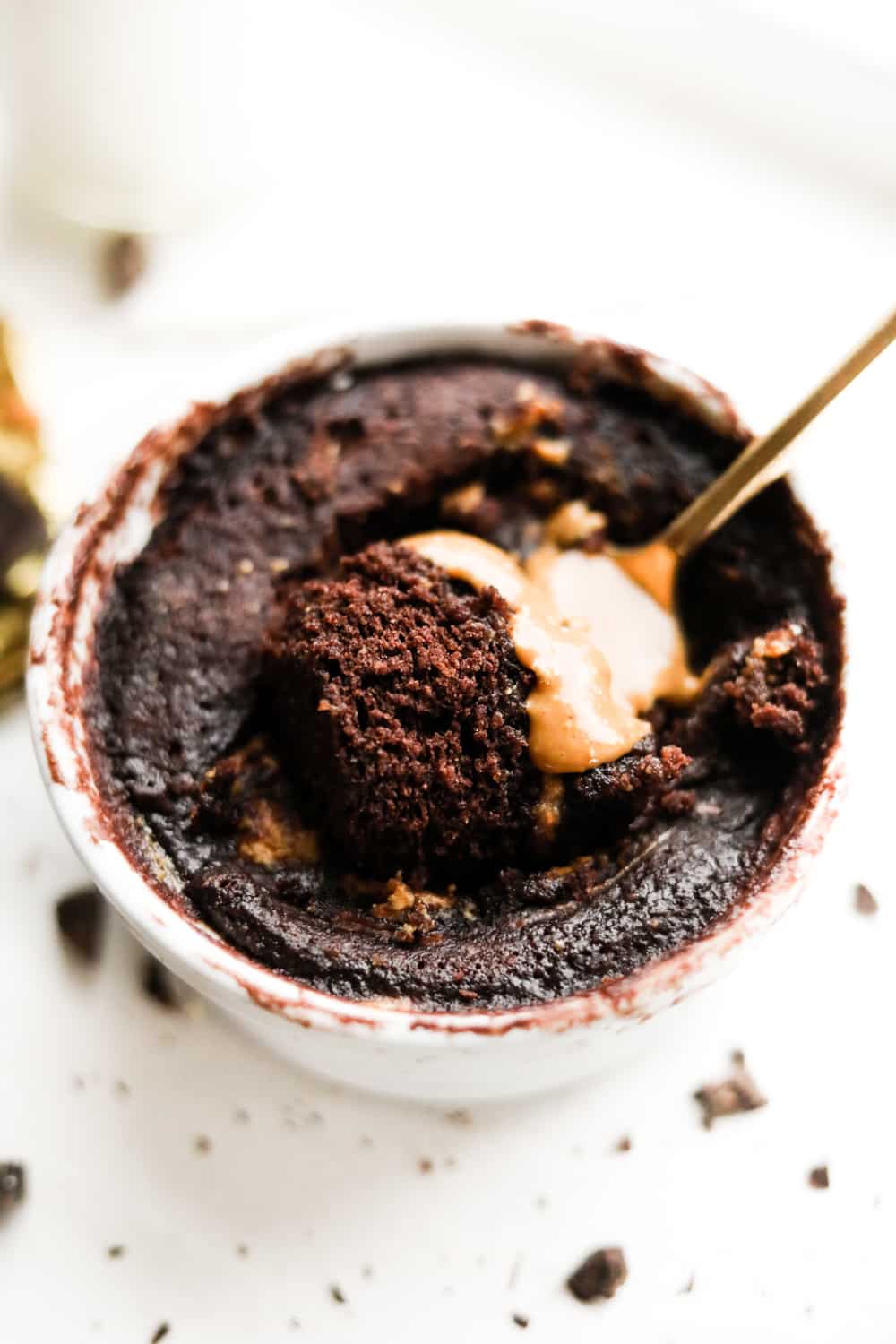 A fork about to take a piece of chocolate and peanut butter cake out of a mug.