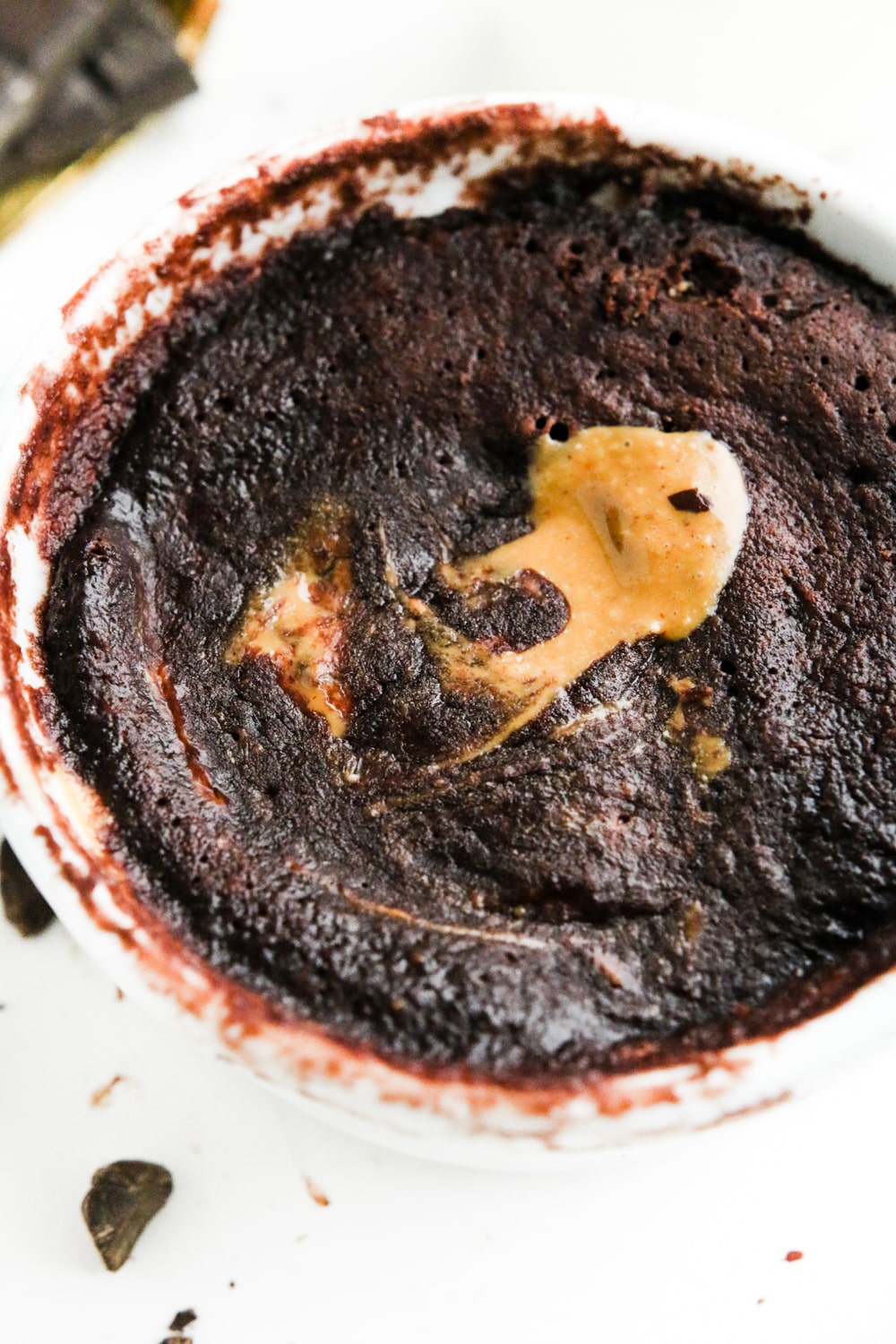 A white ramekin filled with chocolate cake and peanut butter oozing from the center of it.