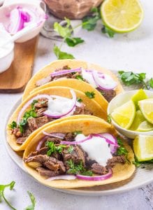 Tortillas filled with carne asada and topped with red onions and sour cream.