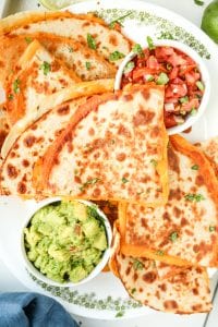 Cheese quesadillas on a white plate stacked on top of one another.