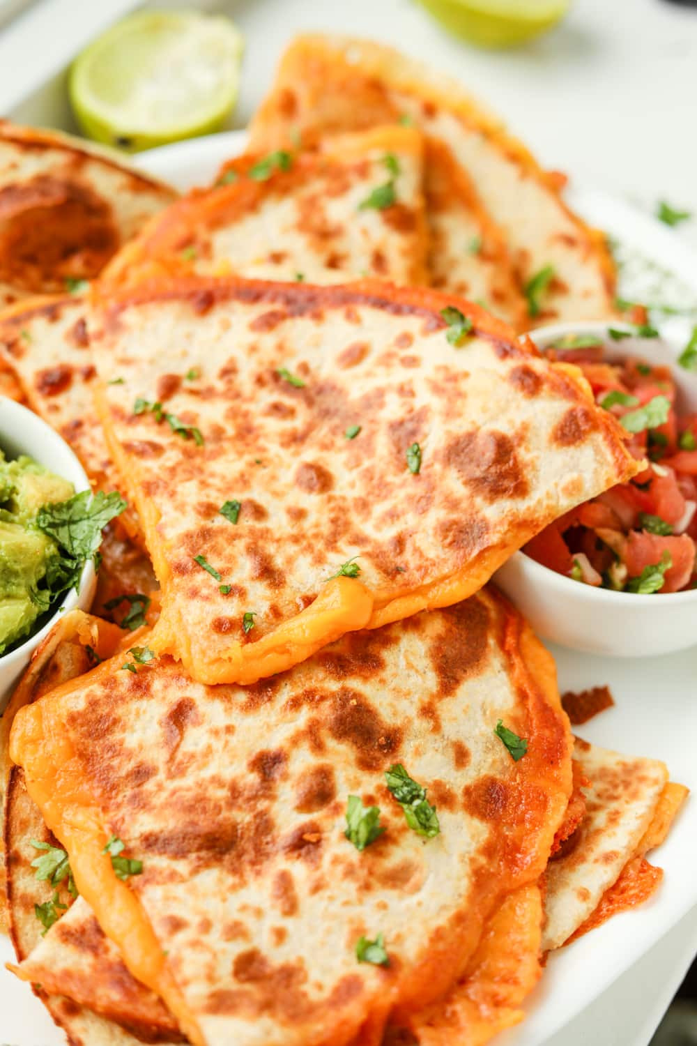 Quesadillas stuffed with cheese on a white plate.