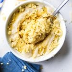 A fork about to take a piece of lemon cake from a mug full of cake.