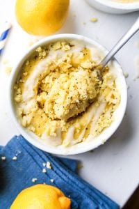 A fork about to take a piece of lemon cake from a mug full of cake.