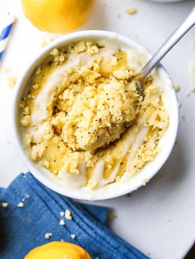 A fork about to take a piece of lemon cake from a mug full of cake.